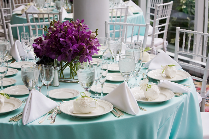 Table setting with blue table cloth and white plates and napkins